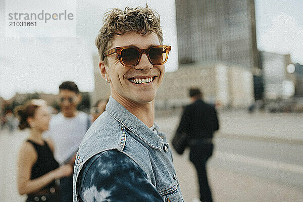 Portrait of smiling young man in sunglasses at street