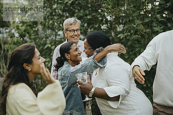 Happy female family members greeting each other at social gathering in back yard