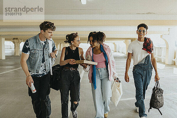 Fashionable male and female friends walking in parking garage with shopping bags