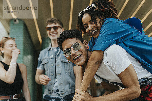 Portrait of young man piggybacking fashionable female friend