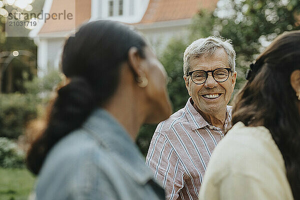 Cheerful senior man discussing with female family friend at garden party