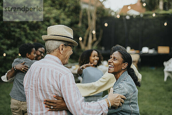 Cheerful male and female family members enjoying during social gathering at garden party