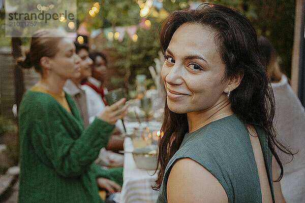 Portrait of smiling woman with friends celebrating in back yard