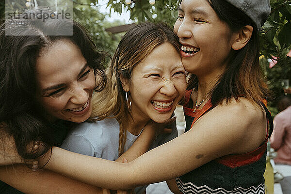 Cheerful multiracial female friends laughing together at dinner party