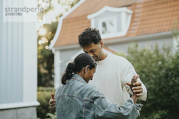 Mature man dancing with female family friend in back yard