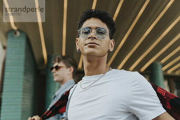 Low angle portrait of young fashionable man in sunglasses and pierced nose