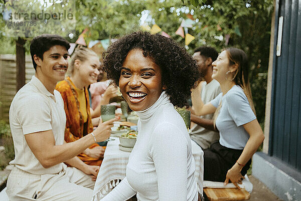 Side view portrait of happy woman with friends at dining table at dinner party