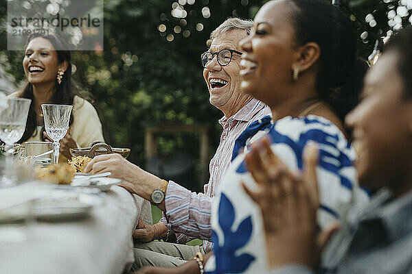 Happy senior man enjoying with family members at lunch party