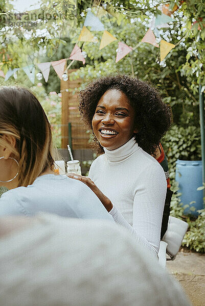 Smiling young woman with curly hair enjoying at dinner party