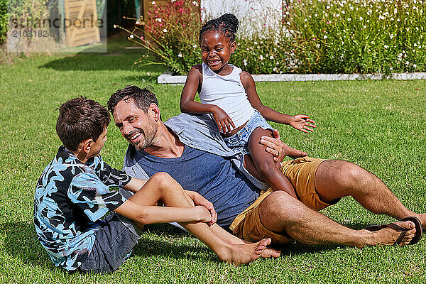 Father with children (6-7  8-9) playing on back yard