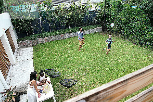 Parents with children (18-22 months  6-7  8-9) playing on back yard