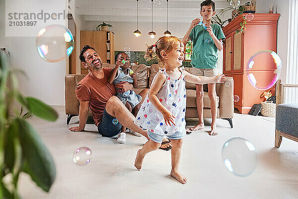 Father with children (18 - 23 months  6-7  8-9) playing with bubbles