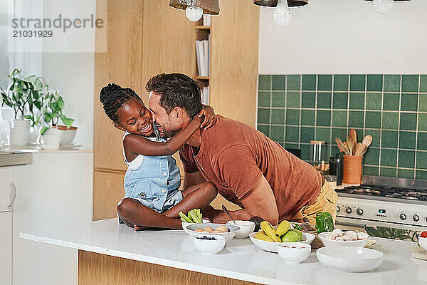 Girl (6-7) embracing smiling father in kitchen