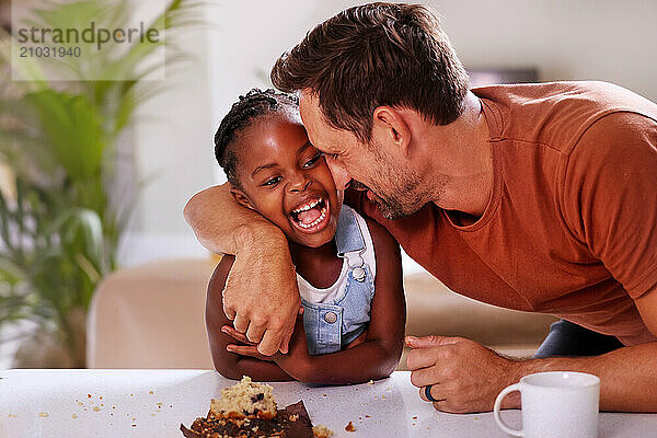 Father embracing smiling daughter (6-7) at home