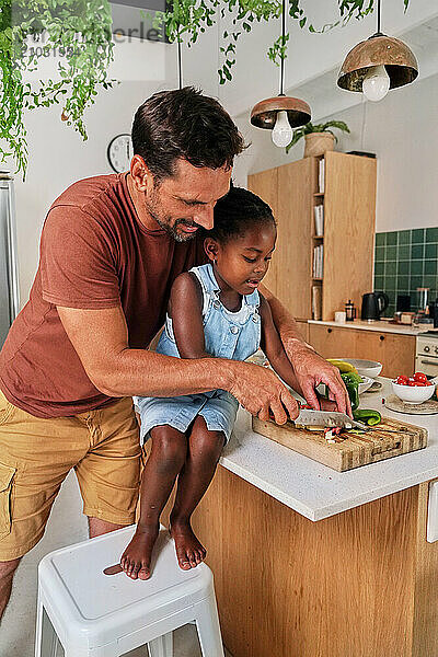 Father and daughter (6-7) cutting vegetables