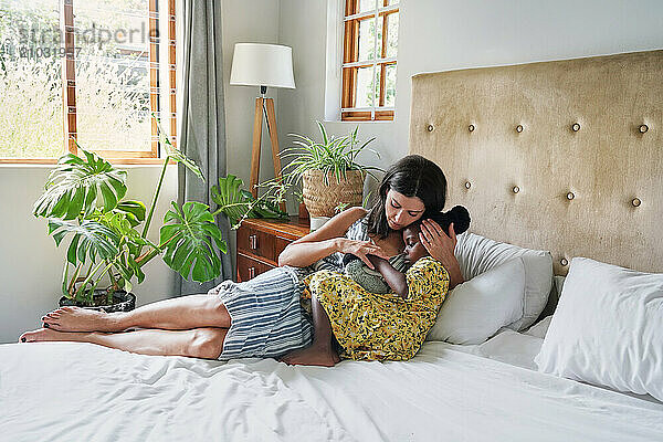 Mother hugging daughter (6-7) on bed