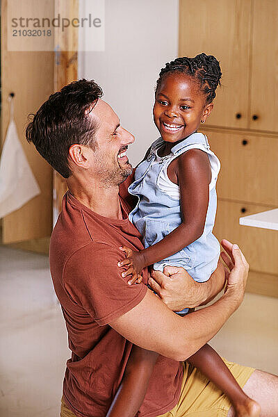 Father carrying smiling daughter (6-7) at home