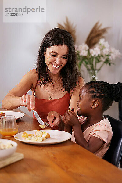 Mother assisting daughter (6-7) eating lunch