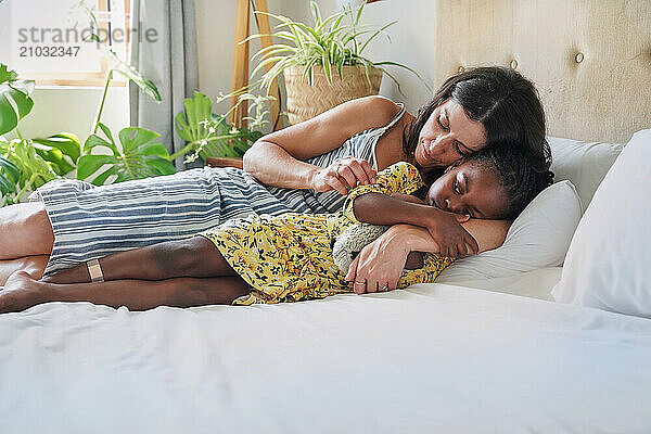 Mother hugging daughter (6-7) on bed