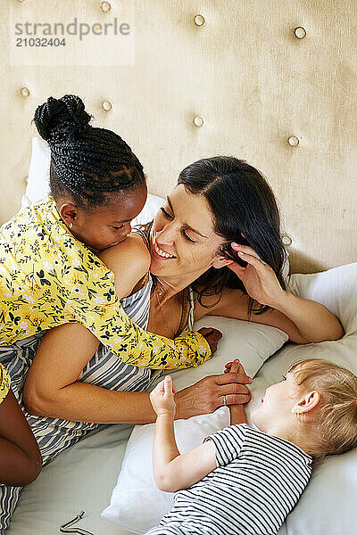 Mother with daughters (18-22 months  6-7) on bed