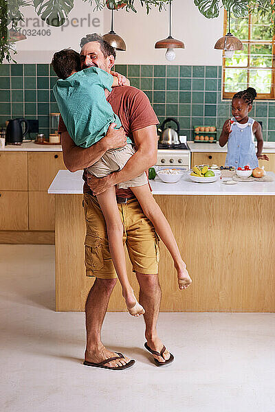 Happy father carrying son (8-9) in kitchen