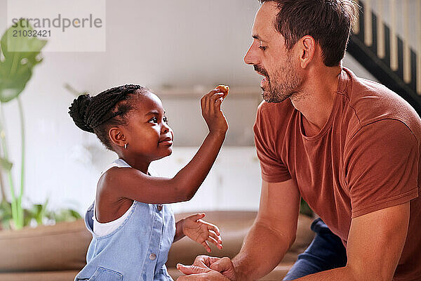 Girl (6-7) feeding father with cake at home