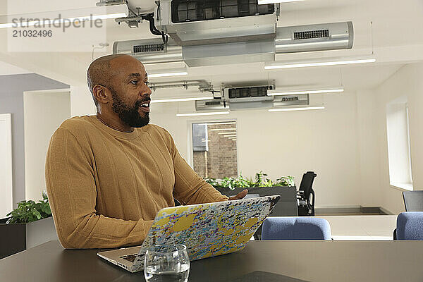 Smiling man with laptop in modern office