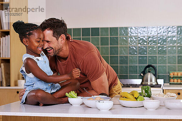 Father embracing smiling daughter (6-7) in kitchen