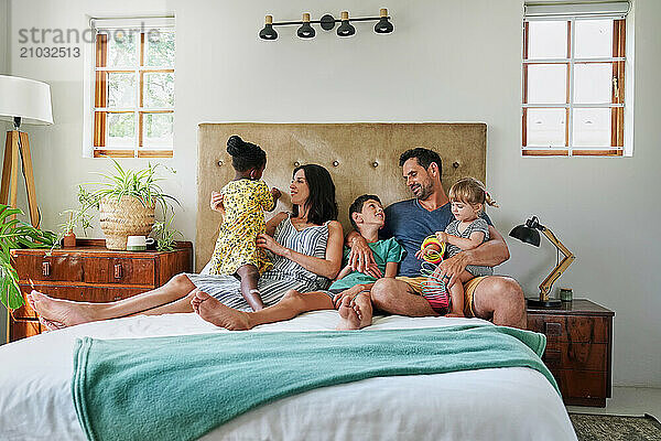 Parents with children (18-22 months  6-7  8-9) relaxing on bed