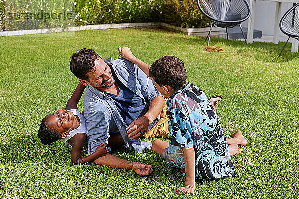 Father with children ( 6-7  8-9) playing on back yard