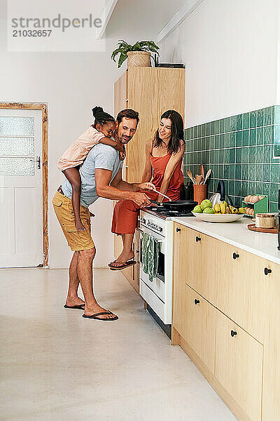 Parents with daughter (6-7) cooking in kitchen