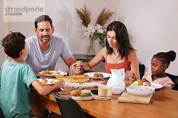 Family saying grace at table