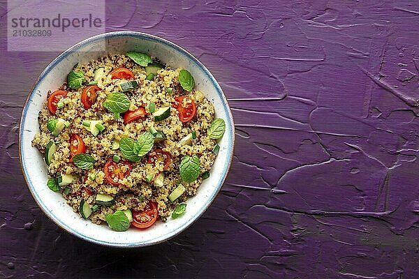 Quinoa tabbouleh salad in a bowl  a healthy dinner with tomatoes and mint  top shot with copy space on a purple background  Food photography  Food photography