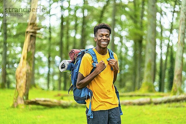 Portrait of a cheerful young african man hiking through green forest