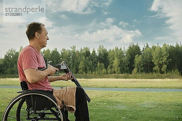 Senior man in wheelchair loading double-barreled shotgun with shells