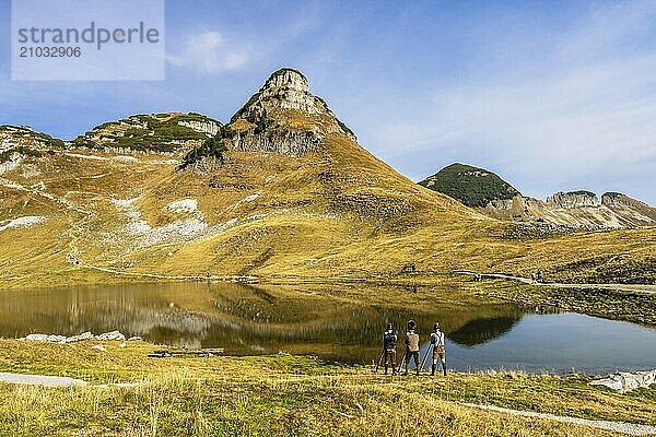 The Austrian alphorn trio Klangholz plays the alphorn at Lake Augstsee on Mount Loser. Mount Atterkogel in the background. Autumn  good weather  blue sky. Reflection. Altaussee  Bad Aussee  Ausseer Land  Totes Gebirge  Styria  Upper Austria  Austria  Europe