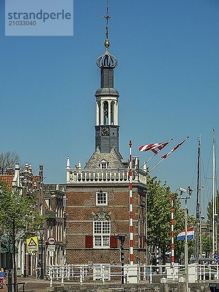 Old building with flags  under a sunny sky  surrounded by other buildings  alkmaar  the netherlands