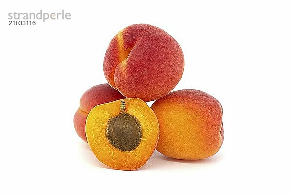 Pile of ripe apricots and one sliced in half to showcase its succulent interior  isolated on a white background