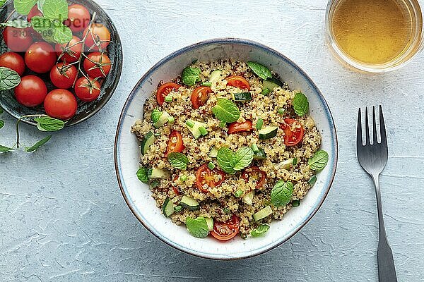 Quinoa tabbouleh salad in a bowl  a healthy dinner with tomatoes and mint  overhead flat lay shot on a blue background  Food photography