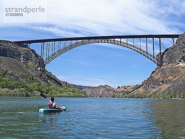 A teenage young man is paddling on the Snake River towards the Perrine Bridge in Twin Falls  Idaho