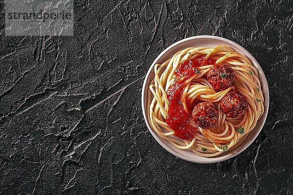 Meatballs. Beef meat balls  overhead flat lay shot with spaghetti pasta  parsley  and tomato sauce  on a black background  with copy space