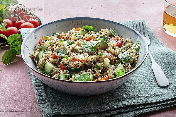 Quinoa tabbouleh salad in a bowl  a healthy dinner with tomatoes and mint  on a pink background  Food photography