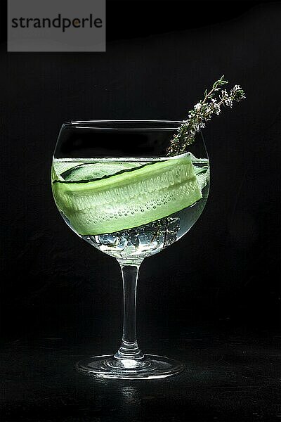 Fresh cocktail. Gin and tonic drink with ice at a party  on a black background. Alcohol with cucumber and thyme  Food photography  Food photography