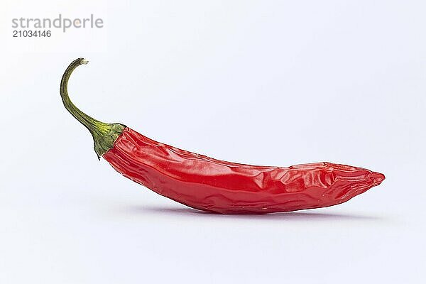 A close up studio photo of a drying red pepper on a white background