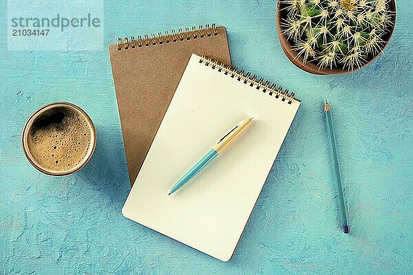 Notebook with a pen  coffee  and plant  overhead flat lay shot on a vibrant blue background  a mockup  Food photography