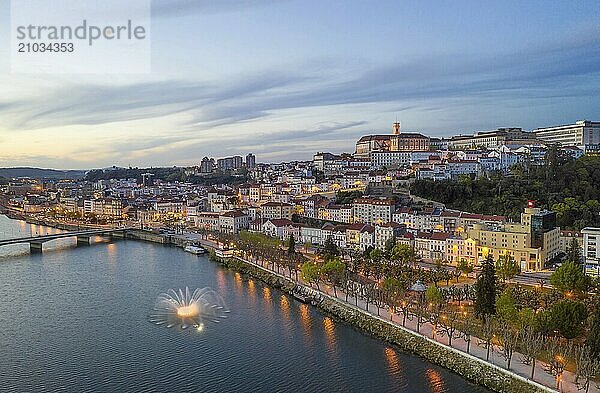 Coimbra drone aerial city view at sunset with colorful fountain in Mondego river and beautiful historic buildings  in Portugal