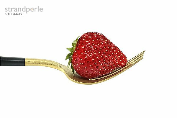 Red strawberry arranged on gold fork with a black handle  set against a white background  symbolizing a concept of healthy diet and organic food