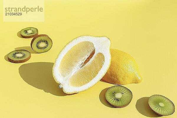 Halves of lemon with shadow  sliced kiwi cuts on yellow background. Healthy eating  travel or vacation concept