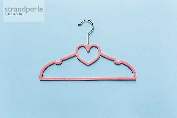 Black Friday or clothing industry concept on blue background flat lay with single one pink clothes hanger with heart shape on hanger