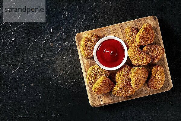 Chicken nuggets with bbq sauce on a black background  shot from above with a place for text. Crispy snack  Food photography